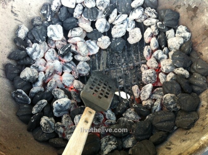 Spreading the coals away from the center of the grill.
